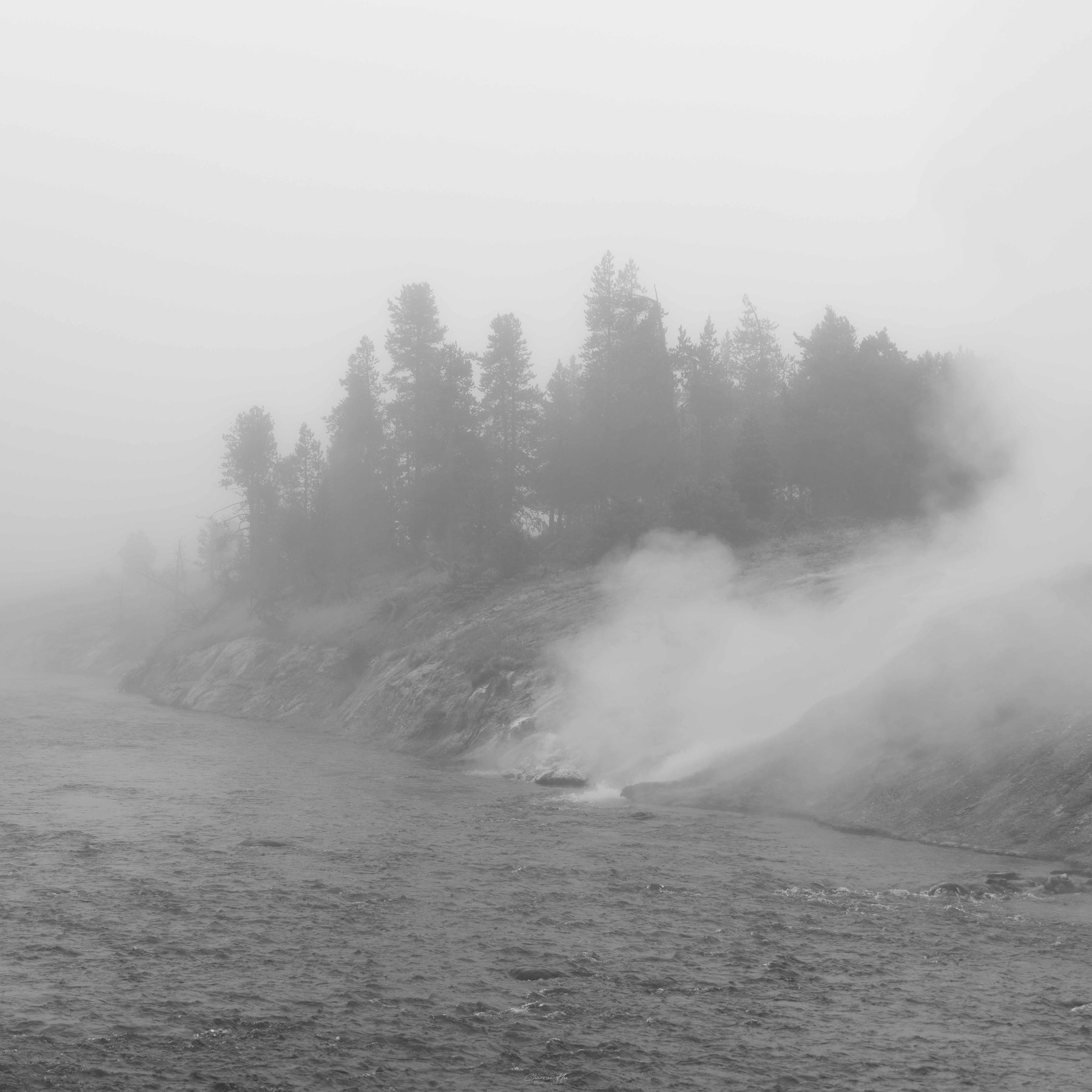 Steam rising by a river in fog, black and white