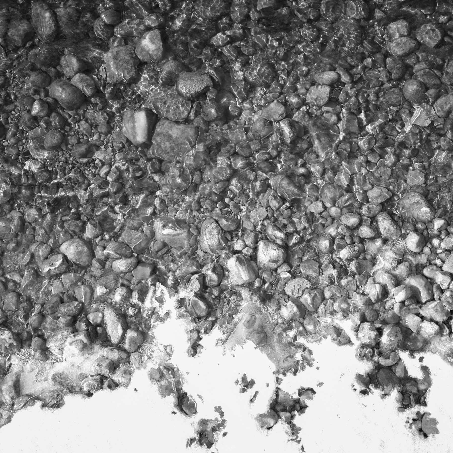 Stones under clear water, black and white